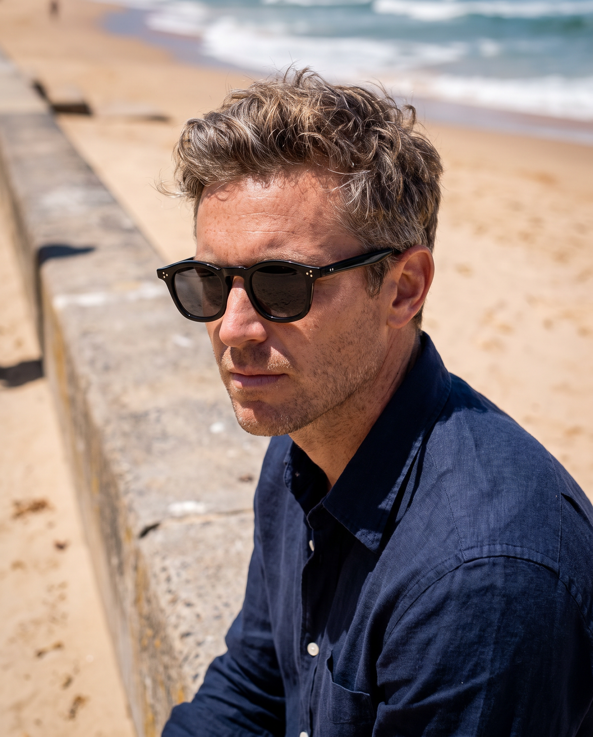 COLLIN zonnebril zwart gedragen door een man aan het strand