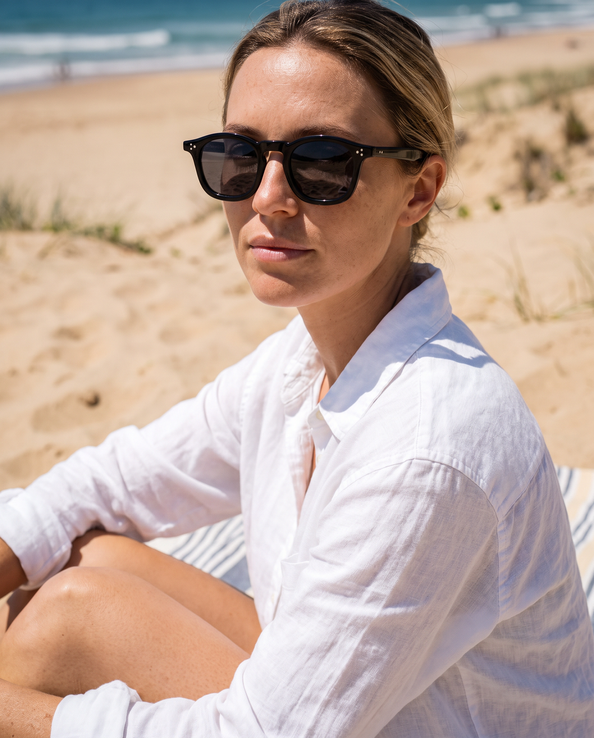COLLIN zonnebril zwart gedragen op het strand in hard middaglicht