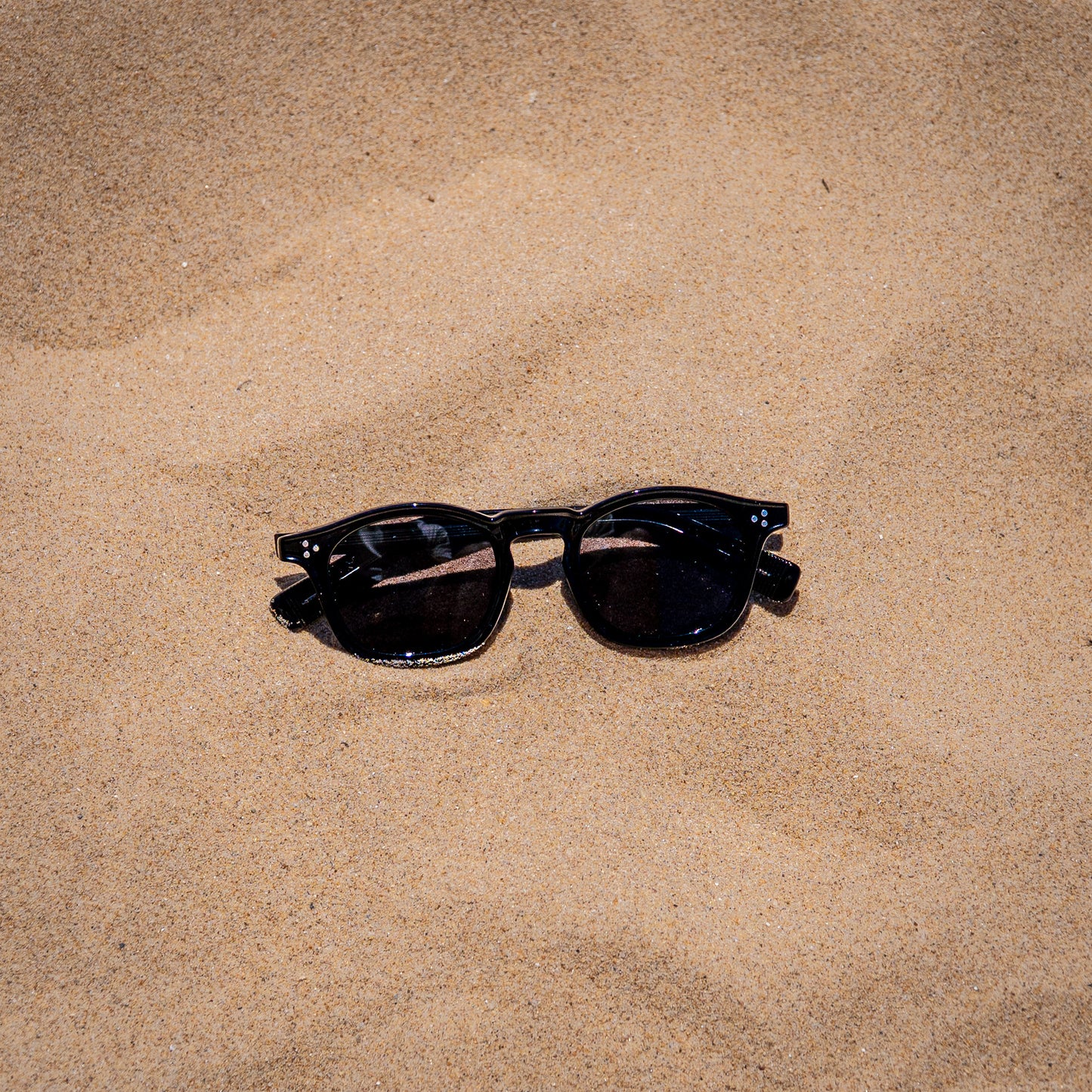 Collin zwarte zonnebril in zand close-up | klassiek unisex design