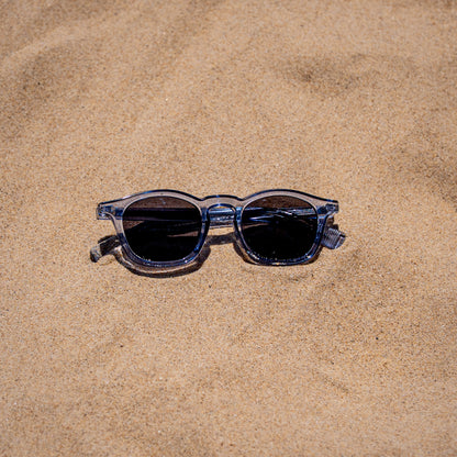 Collin blauwe zonnebril close-up in zand | opvallende kleur met UV400 bescherming