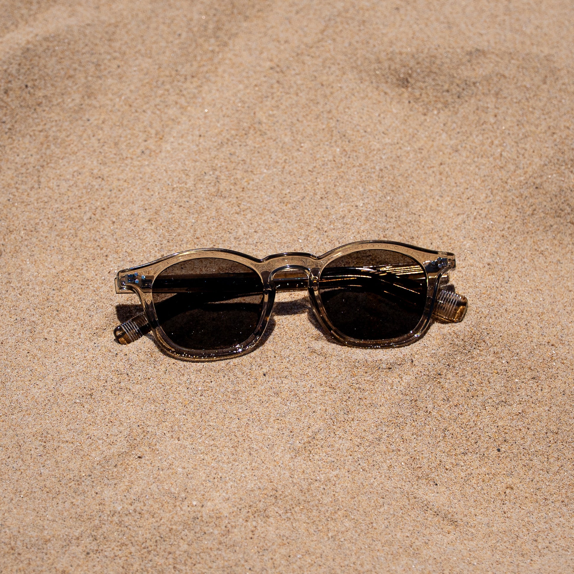 Collin tea zonnebril in het zand | vintage look met grijze glazen