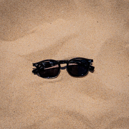 Collin zwarte zonnebril in zand close-up | klassiek unisex design