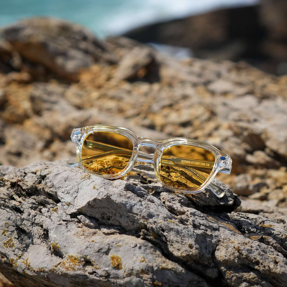 TIBOR, transparent with yellow lenses, on a stone by the coast